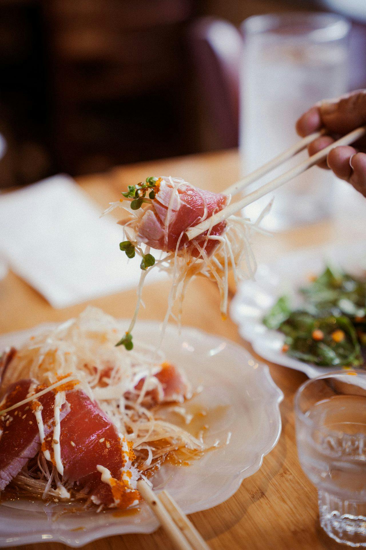 person holding raw fish with chopsticks