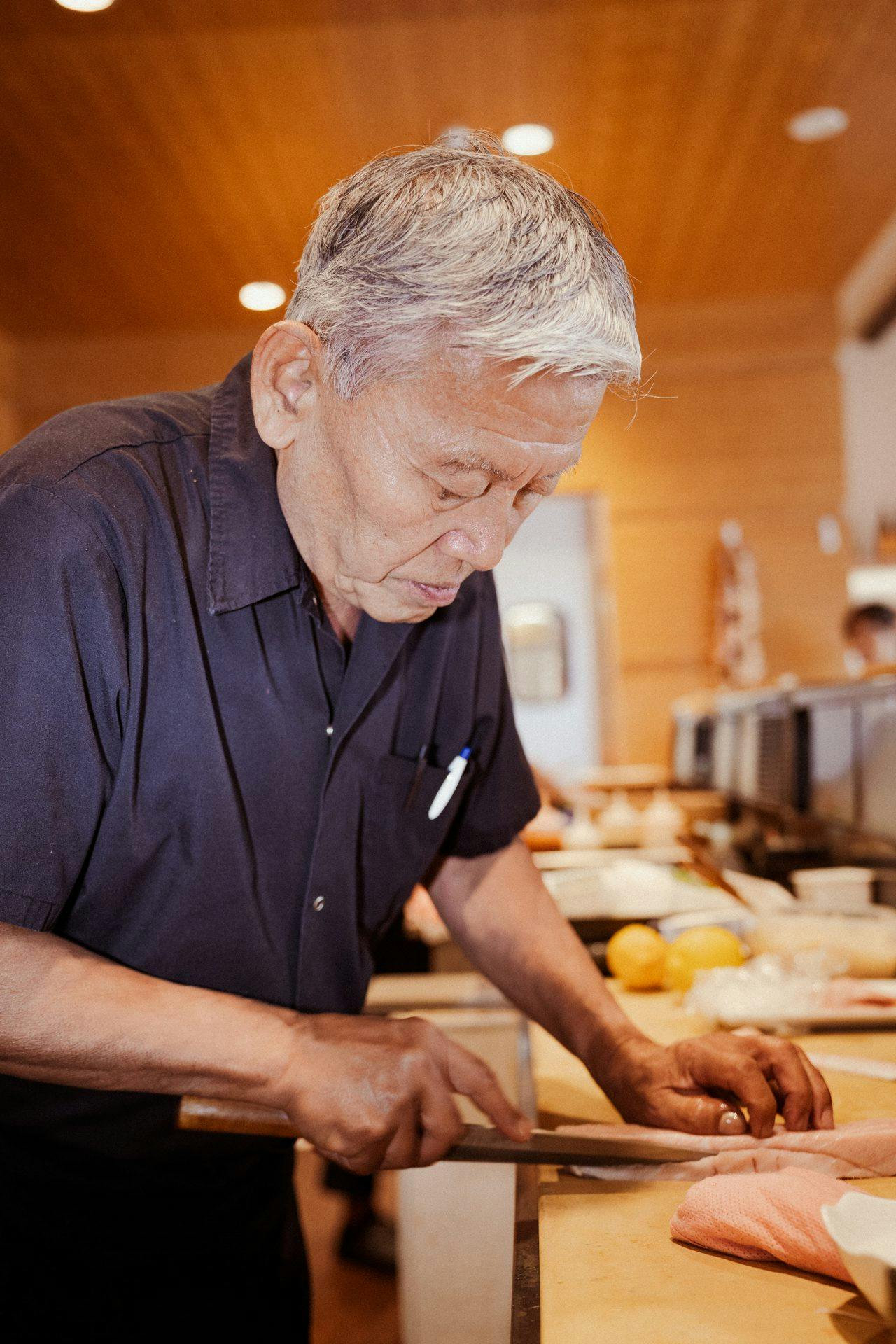 older person slicing sashimi